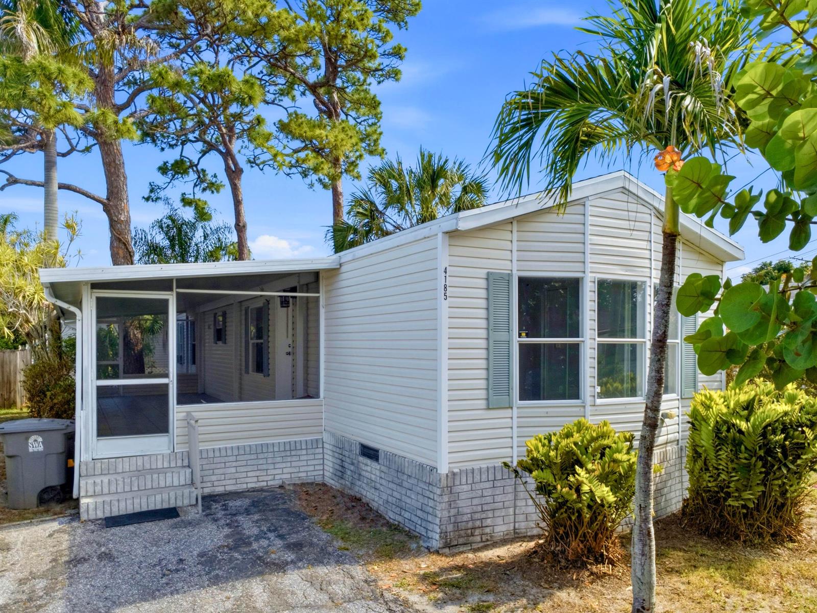 A single-story manufactured home with light siding, a brick base, and an attached screened porch — 4185 N Shady Lane, Boynton Beach FL 33436, BOYNTON BEACH, FL