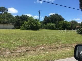 A grassy, vacant lot features scattered trees and a utility pole under a blue sky — 106 GULF AVENUE, NOKOMIS, FL
