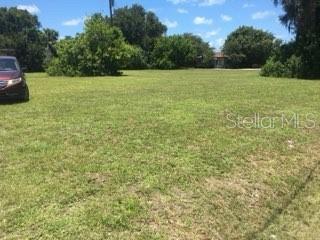 A grassy, vacant lot is shown with trees in the background and a car parked nearby — 106 GULF AVENUE, NOKOMIS, FL