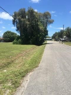 A grassy vacant lot sits beside a paved road with a large tree in the background — 106 GULF AVENUE, NOKOMIS, FL