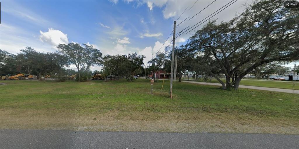 A grassy vacant lot with several mature trees and a utility pole under a blue sky — N/A, POLK CITY, FL