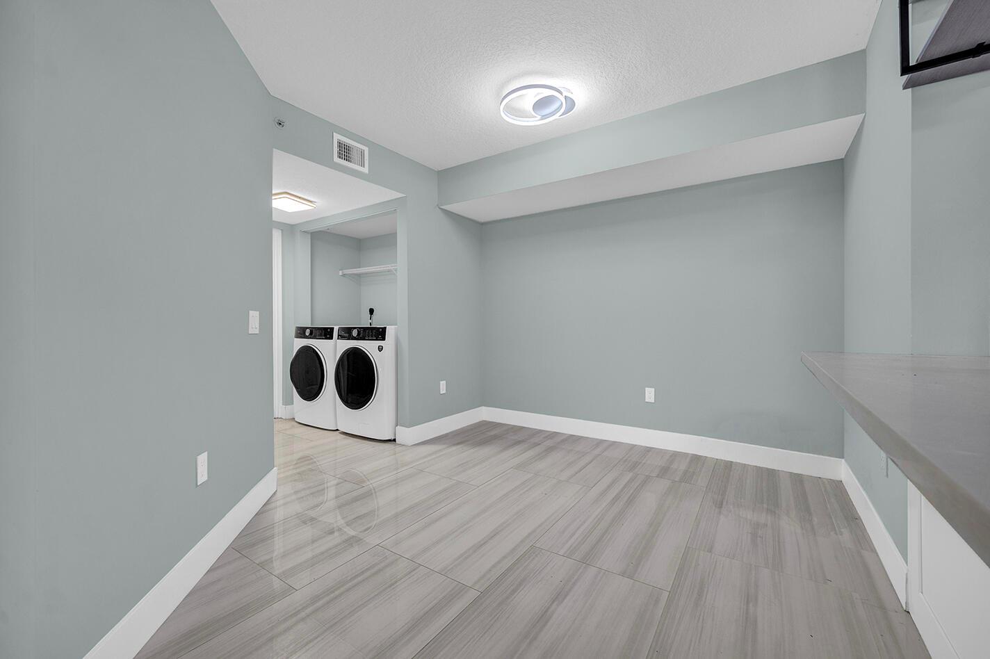A laundry room with light blue walls, gray wood-look tile flooring, and a white washer-dryer set — 1010 Villa Circle, Boynton Beach FL 33435, BOYNTON BEACH, FL