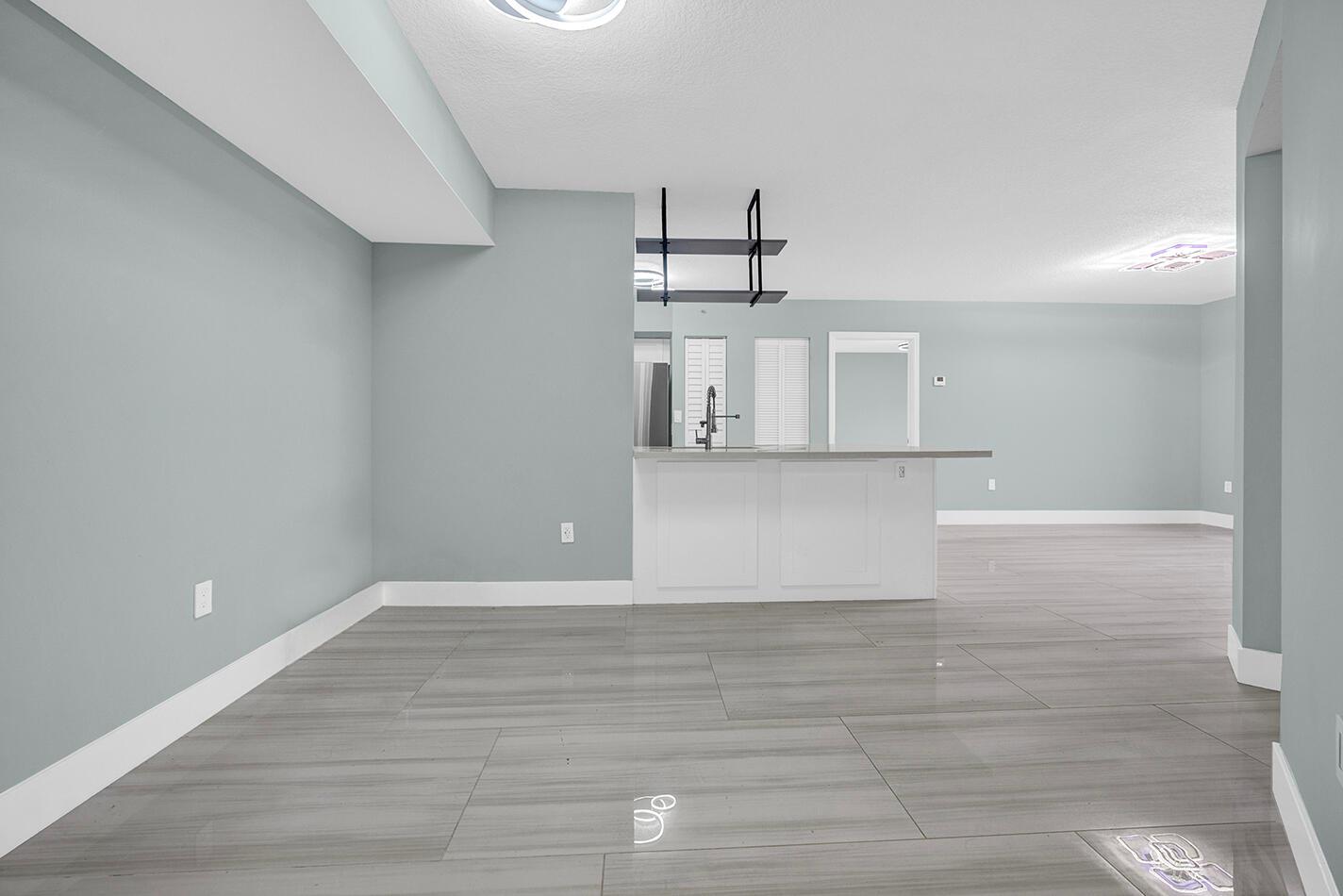 A dining area with gray walls and wood-look tile flooring opens to a kitchen island — 1010 Villa Circle, Boynton Beach FL 33435, BOYNTON BEACH, FL