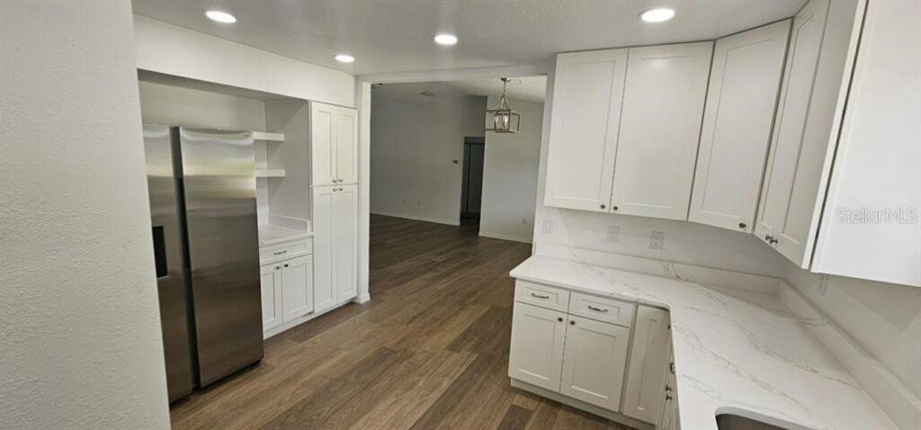 A kitchen features white cabinets, stainless steel appliances, and light countertops with wood-look flooring — 10842 SW 90TH COURT, OCALA, FL