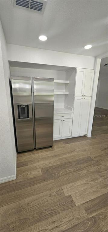A stainless steel refrigerator stands next to white cabinets and open shelving in a kitchen — 10842 SW 90TH COURT, OCALA, FL