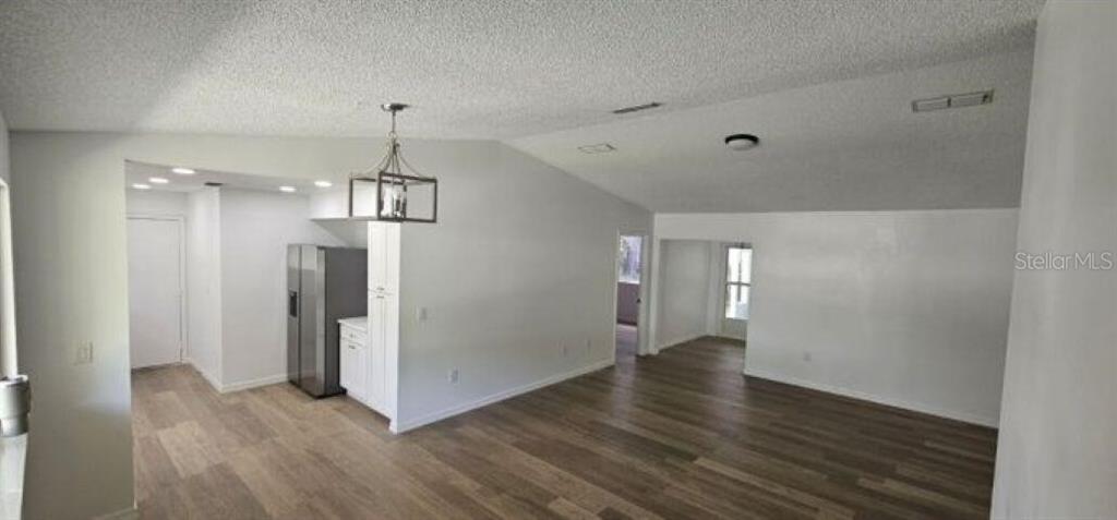 An open-concept living area features light wood-look flooring, white walls, and a modern pendant light — 10842 SW 90TH COURT, OCALA, FL