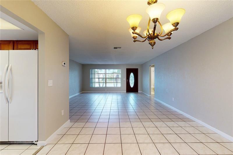 A tiled dining area leads into a living room with a front door and chandelier — 9728 SW 3rd Street, Boca Raton FL 33428, BOCA RATON, FL