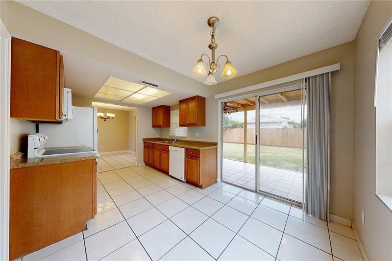 A kitchen with wood cabinets, white tile floors, and a sliding glass door to a patio — 9728 SW 3rd Street, Boca Raton FL 33428, BOCA RATON, FL