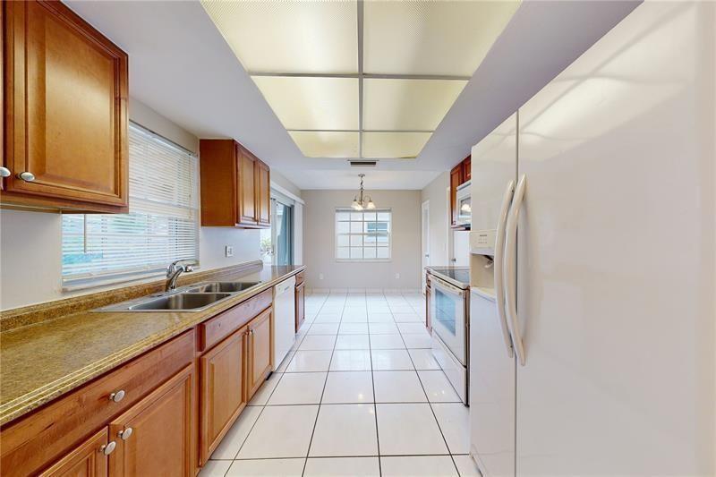 A kitchen with wood cabinets, granite countertops, white appliances, and white tile flooring — 9728 SW 3rd Street, Boca Raton FL 33428, BOCA RATON, FL