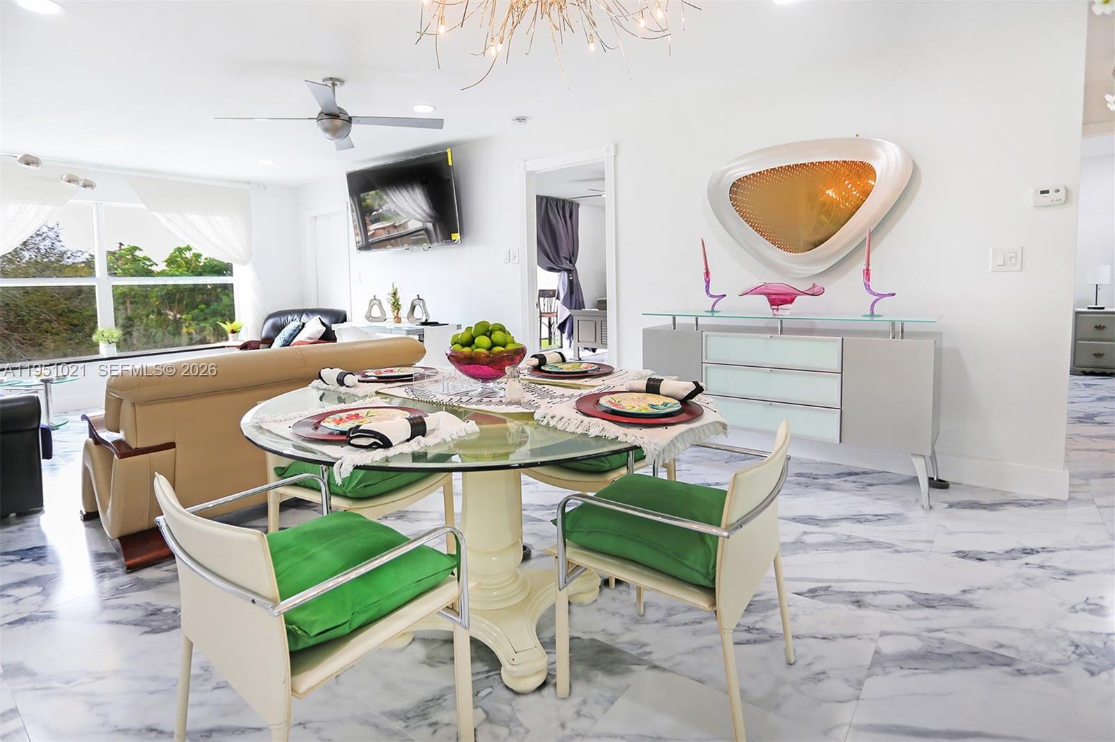 A dining area features a glass table with green cushions, marble flooring, and modern decor — 6570 Royal Palm Blvd # 301J, Margate FL 33063, MARGATE, FL