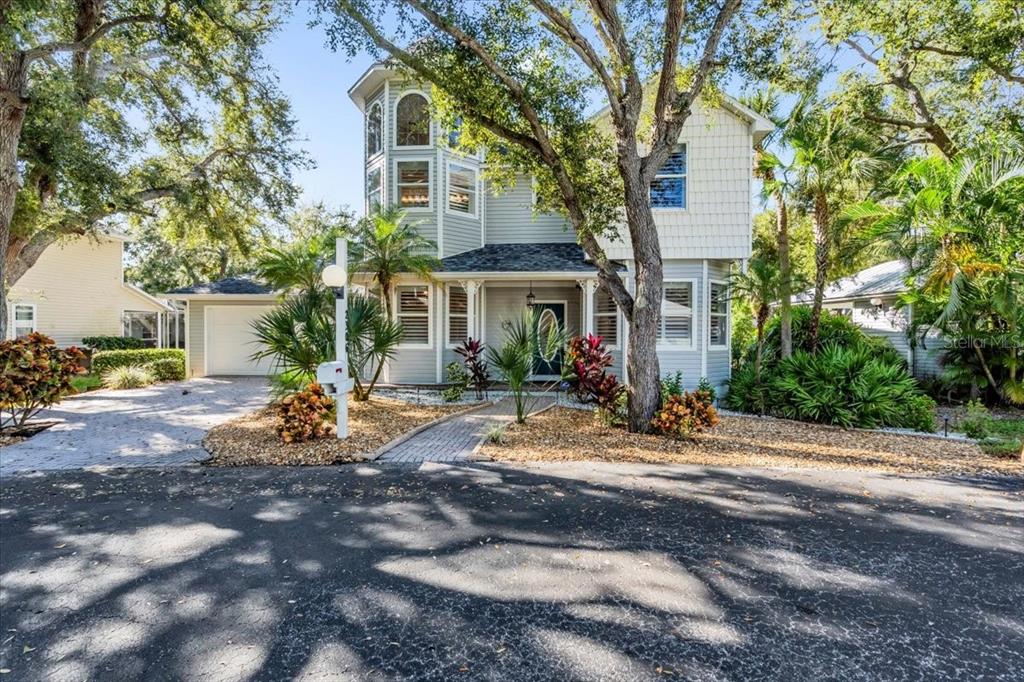 A two-story light gray house with a turret, a paved walkway, and mature trees — 2306 64TH STREET W, BRADENTON, FL