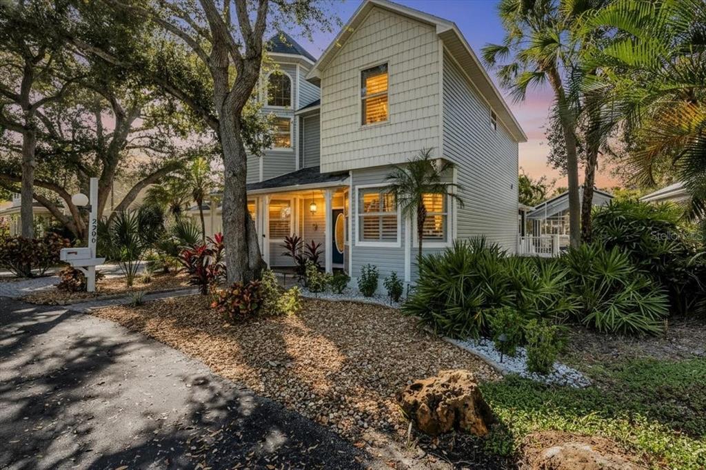 A two-story house with light gray siding and a turret stands behind a gravel yard — 2306 64TH STREET W, BRADENTON, FL