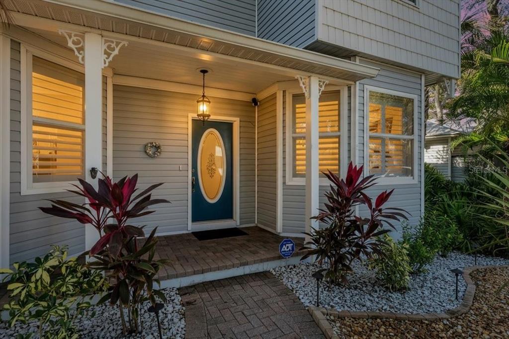 A front porch with a blue door, gray siding, and landscaping in front of a house — 2306 64TH STREET W, BRADENTON, FL