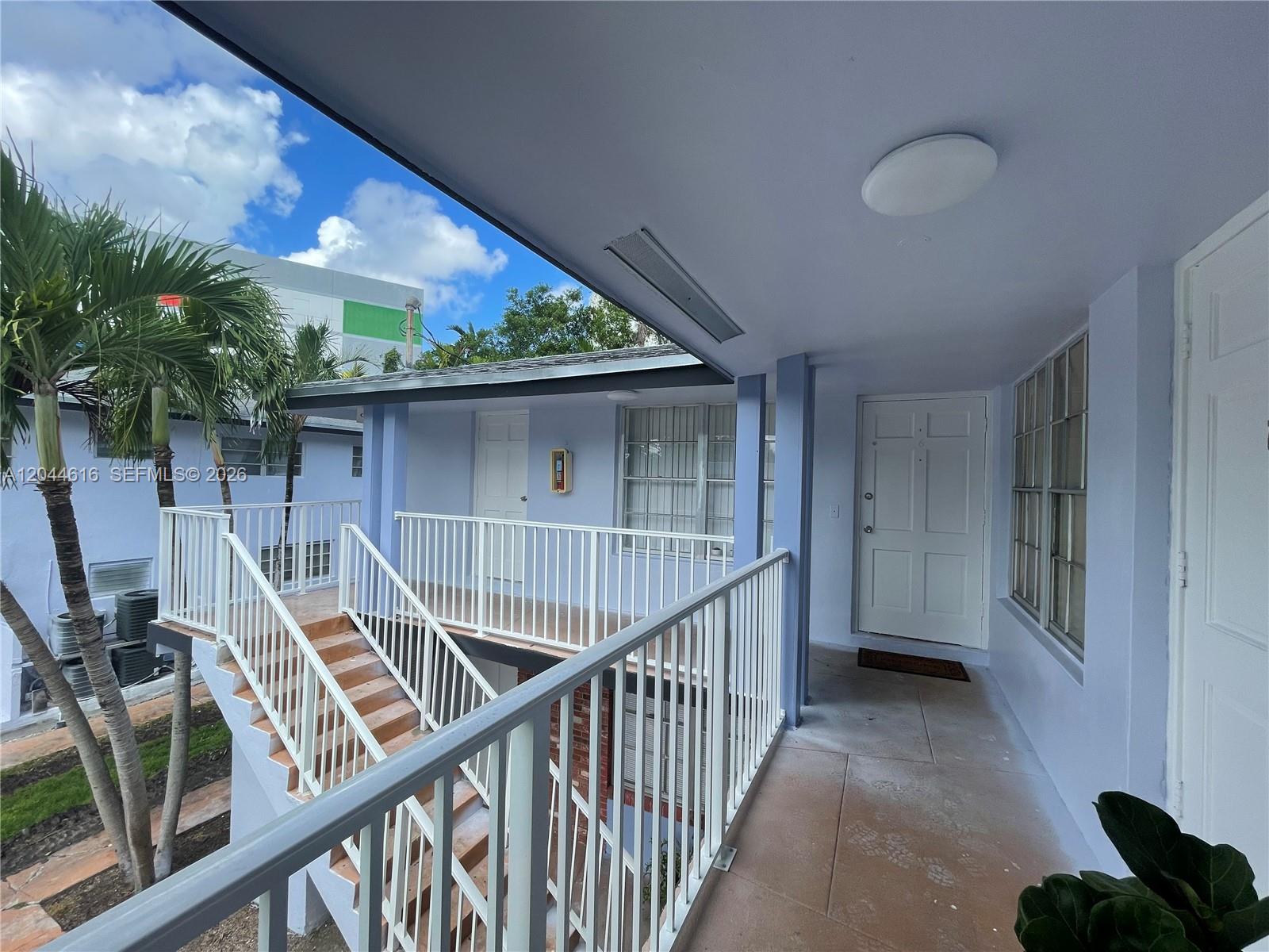 An exterior view shows a second-story walkway with white railings and stairs leading down — 7841 Dunham Blvd # 6, Miami FL 33138, MIAMI, FL