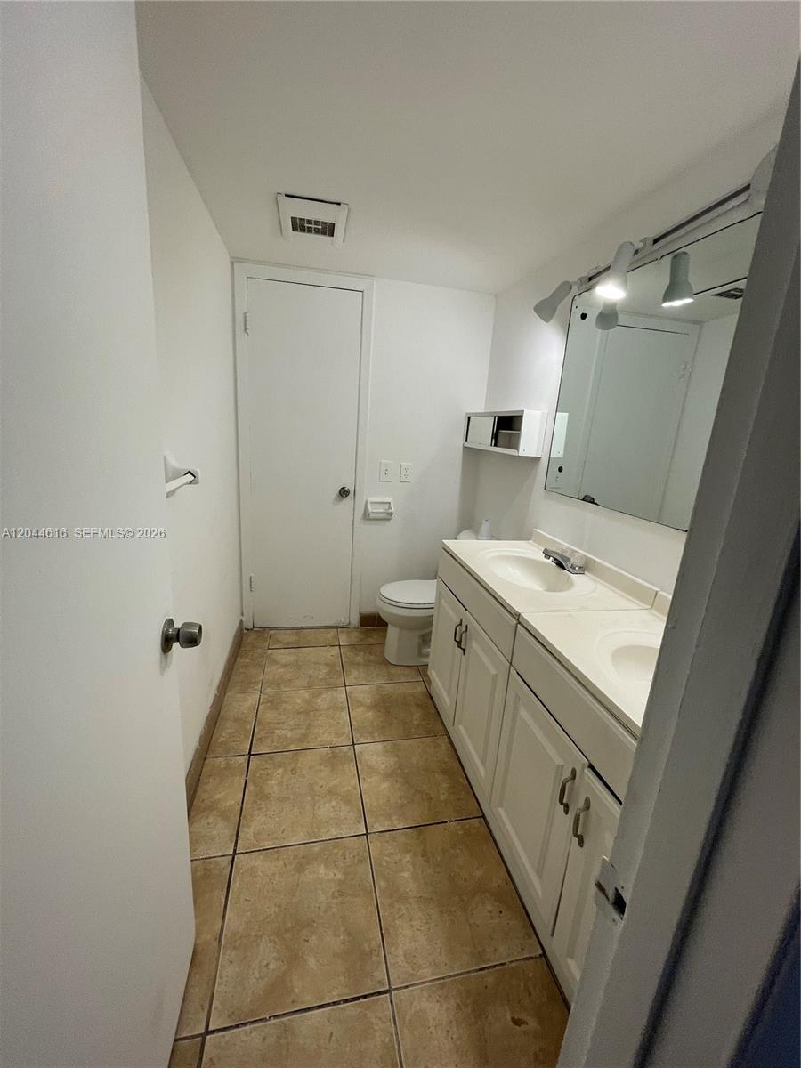 A bathroom features a double vanity with white cabinets, a mirror, and tiled flooring — 7841 Dunham Blvd # 6, Miami FL 33138, MIAMI, FL