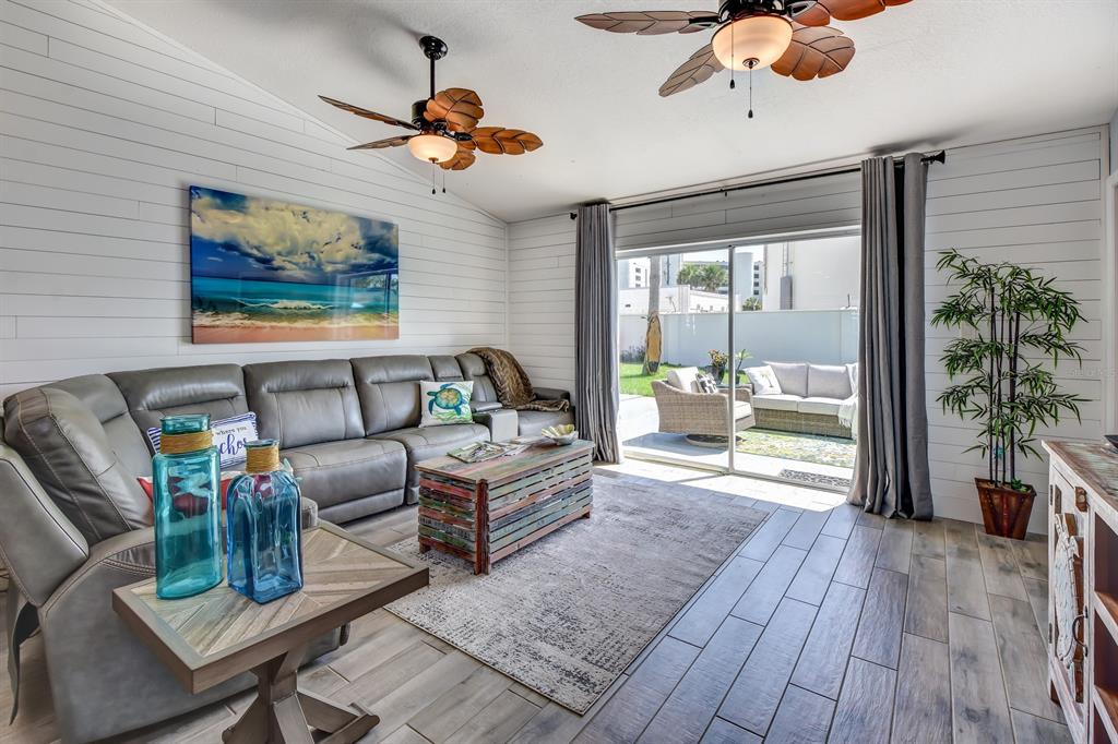 A living room with a grey sectional, shiplap walls, and a sliding door to a patio — 4439 Katy DRIVE, NEW SMYRNA BEACH, FL