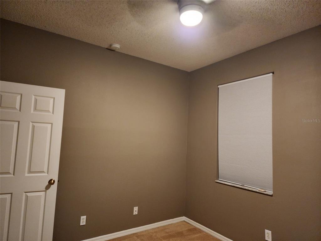 A bedroom with brown walls, a ceiling fan, a white door, and a window — 4025 SHAWN CIRCLE, ORLANDO, FL