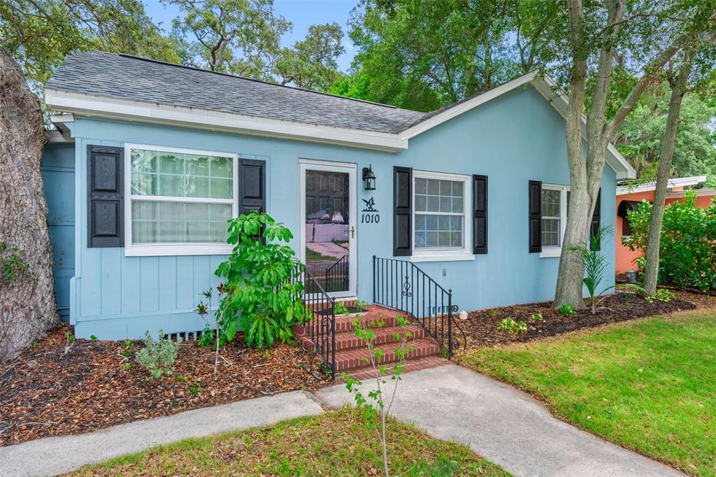 A light blue house with black shutters, a brick front stoop, and a concrete walkway — 1010 OSAGE STREET, CLEARWATER, FL