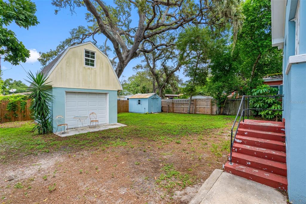 A backyard features a detached garage, a small shed, and red stairs leading to a house — 1010 OSAGE STREET, CLEARWATER, FL