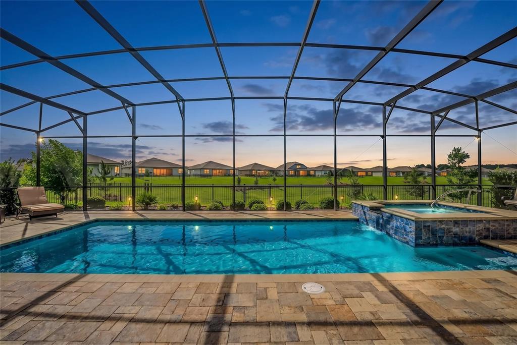A screened-in swimming pool and hot tub overlook a grassy backyard and suburban houses — 6038 SW 86TH CIRCLE, OCALA, FL