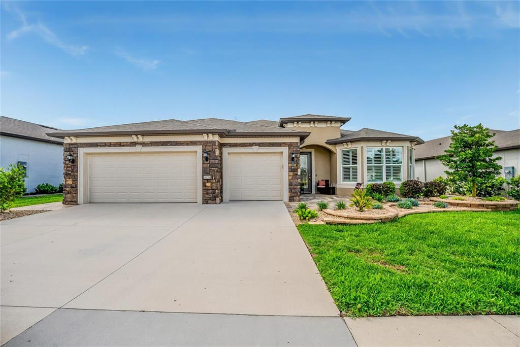 A single-story house with a two-car garage, stone facade, and a landscaped front lawn — 6038 SW 86TH CIRCLE, OCALA, FL