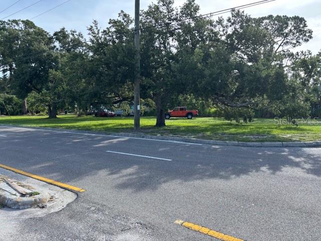 A grassy vacant lot features several large trees and an orange truck parked in back — SWIFT ROAD, SARASOTA, FL