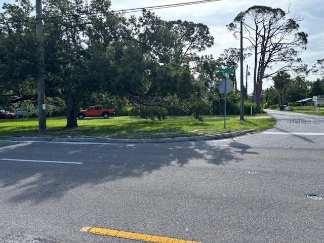 A vacant grassy corner lot features a large tree and a parked red pickup truck — SWIFT ROAD, SARASOTA, FL