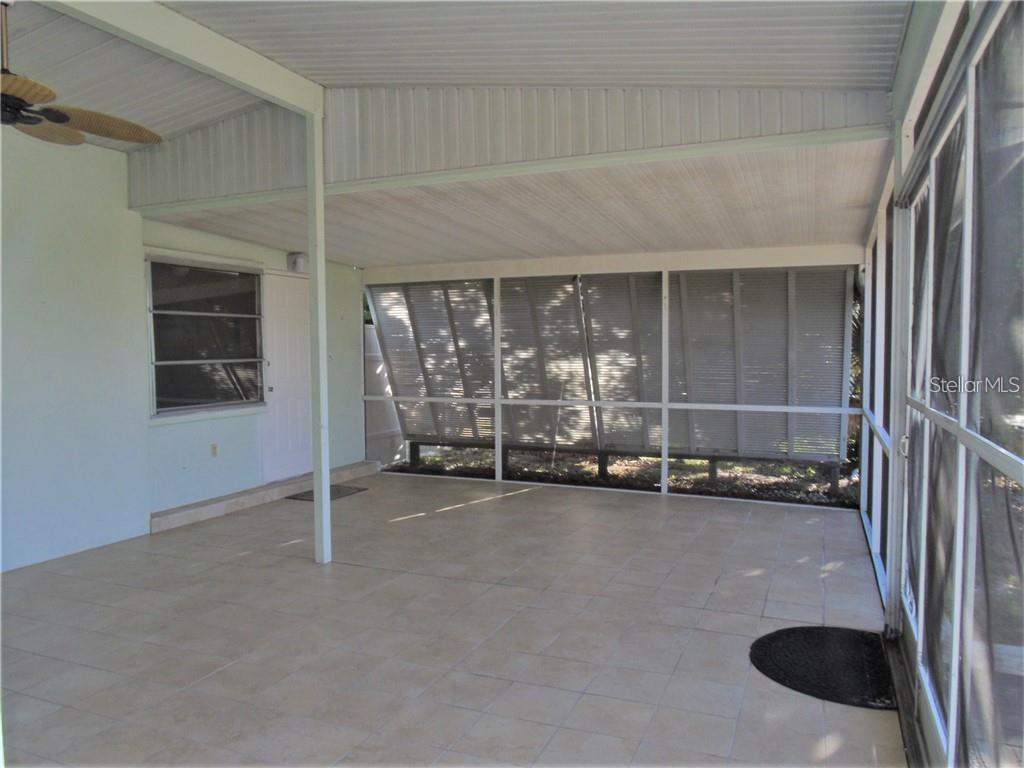 A screened-in porch with tiled flooring, a ceiling fan, and white support columns — 21100 MCGUIRE AVENUE, PORT CHARLOTTE, FL