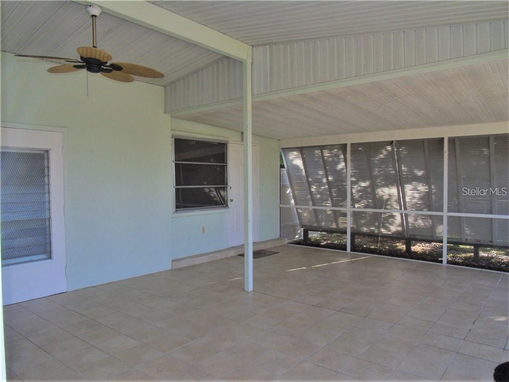 A covered patio features tiled flooring, a ceiling fan, and screened-in walls — 21100 MCGUIRE AVENUE, PORT CHARLOTTE, FL