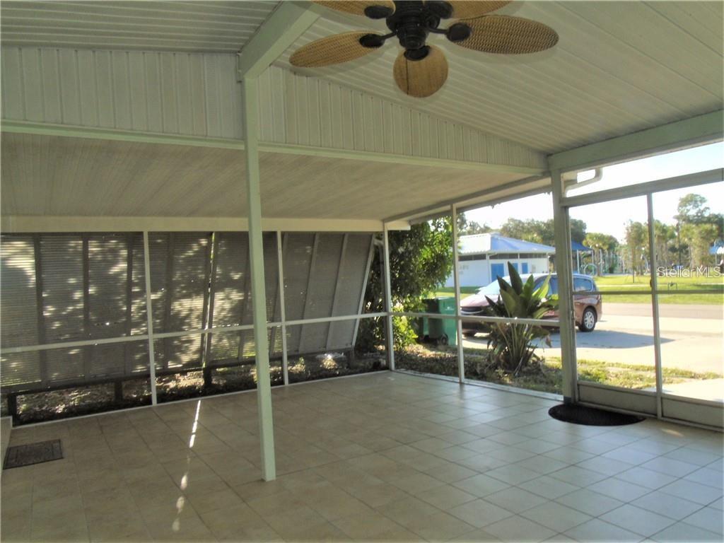 A screened-in patio features tiled flooring, a ceiling fan, and views of a neighborhood street — 21100 MCGUIRE AVENUE, PORT CHARLOTTE, FL