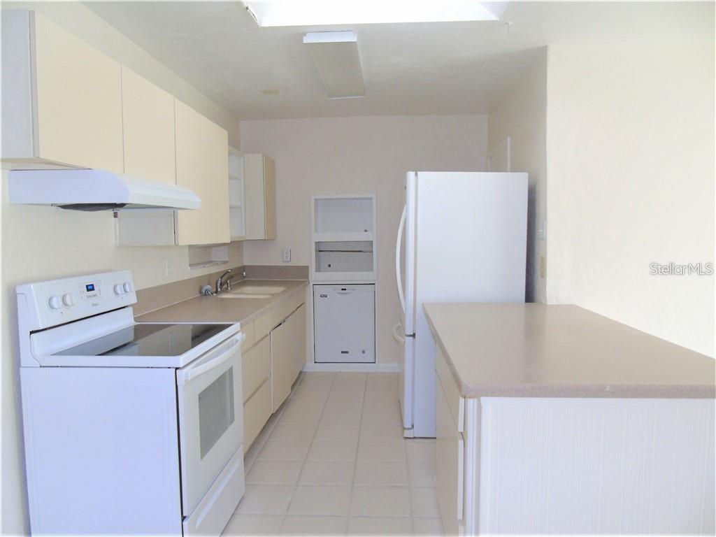 A kitchen with white appliances, light-colored cabinets, beige countertops, and tile flooring — 21100 MCGUIRE AVENUE, PORT CHARLOTTE, FL