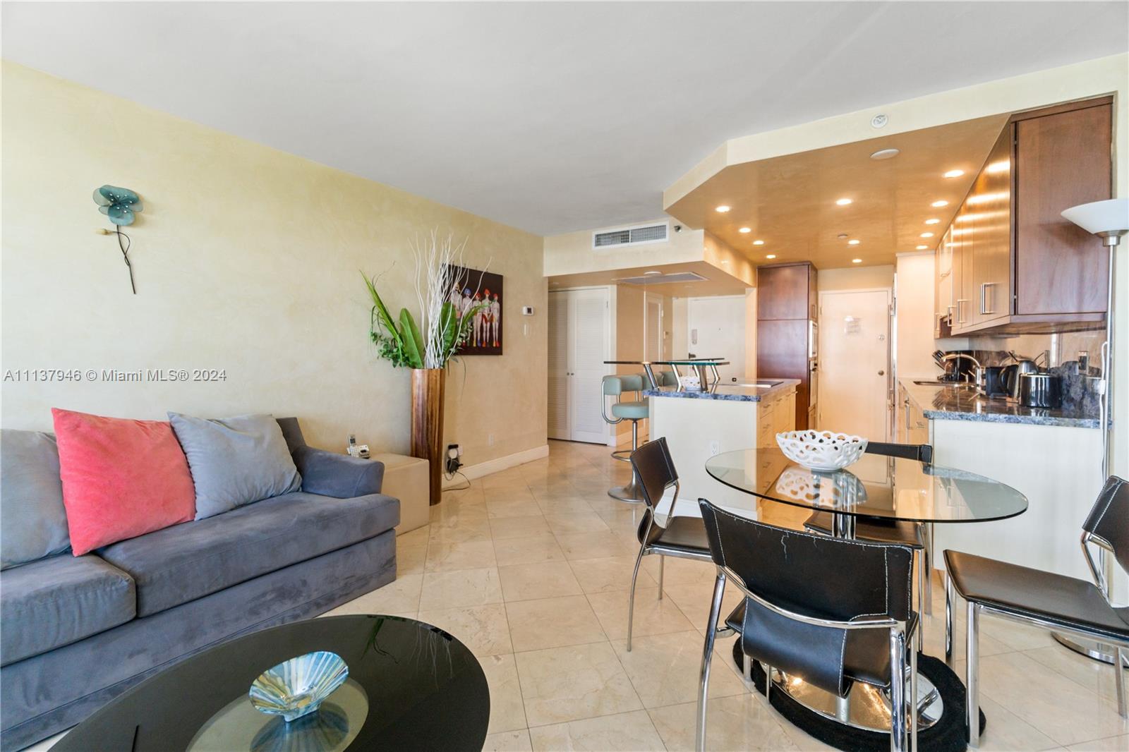 A living room and kitchen area features tile flooring, a grey sofa, and a dining table — 100 Lincoln Rd # 1533, Miami Beach FL 33139, MIAMI BEACH, FL