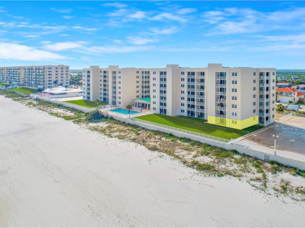 An aerial view of a beachfront condominium building with a swimming pool and grassy lawn — 4495 S ATLANTIC AVENUE UNIT 104, PONCE INLET, FL