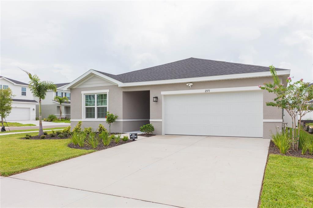 A single-story house with a gray stucco exterior, a two-car garage, and a concrete driveway — 2371 SCENIC PARK LOOP, WIMAUMA, FL
