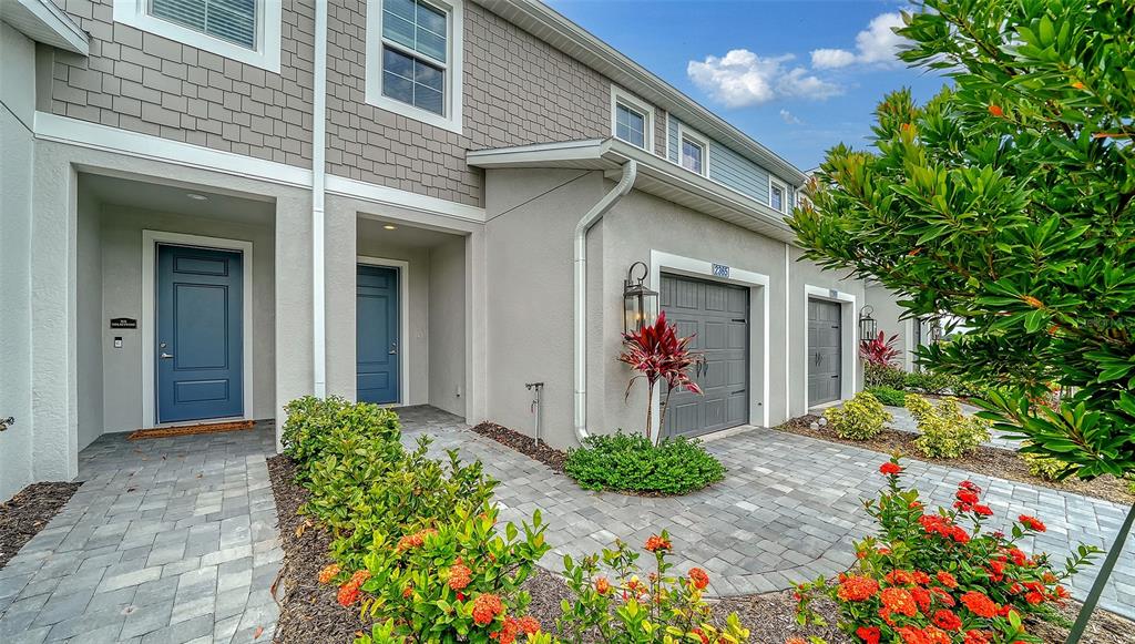 A two-story townhouse exterior features blue doors, gray garage doors, and a paved walkway — 2365 WASHINGTON PALM COURT, BRADENTON, FL