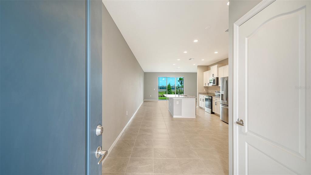 A view from a doorway looking into an open-concept kitchen and living area with tile floors — 2365 WASHINGTON PALM COURT, BRADENTON, FL