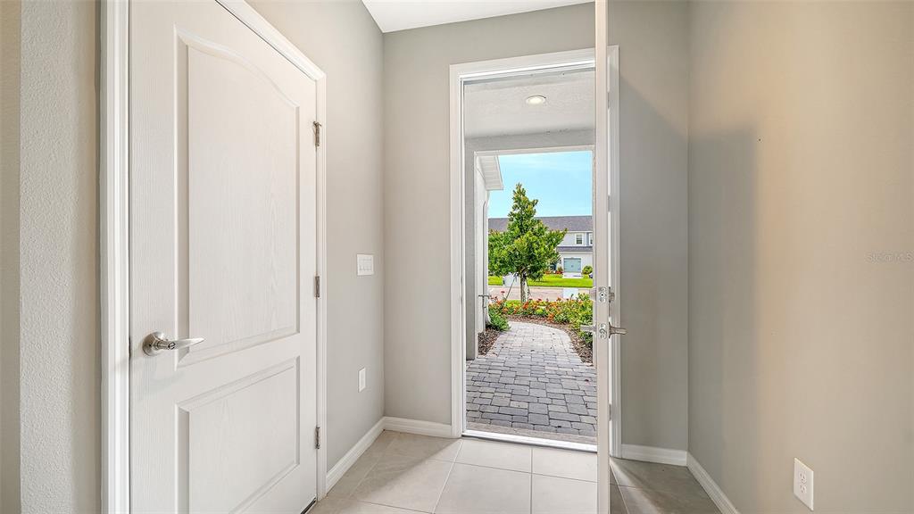 An entryway with light tile flooring, a white interior door, and an open front door — 2365 WASHINGTON PALM COURT, BRADENTON, FL