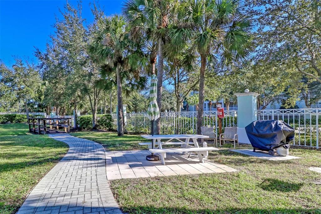 A light green building with a green metal roof surrounded by palm trees and landscaping — 5123 MELBOURNE STREET UNIT D106, PORT CHARLOTTE, FL