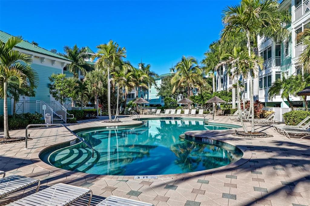A dining room with multiple tables, rattan chairs, large windows, and a tray ceiling — 5123 MELBOURNE STREET UNIT D106, PORT CHARLOTTE, FL