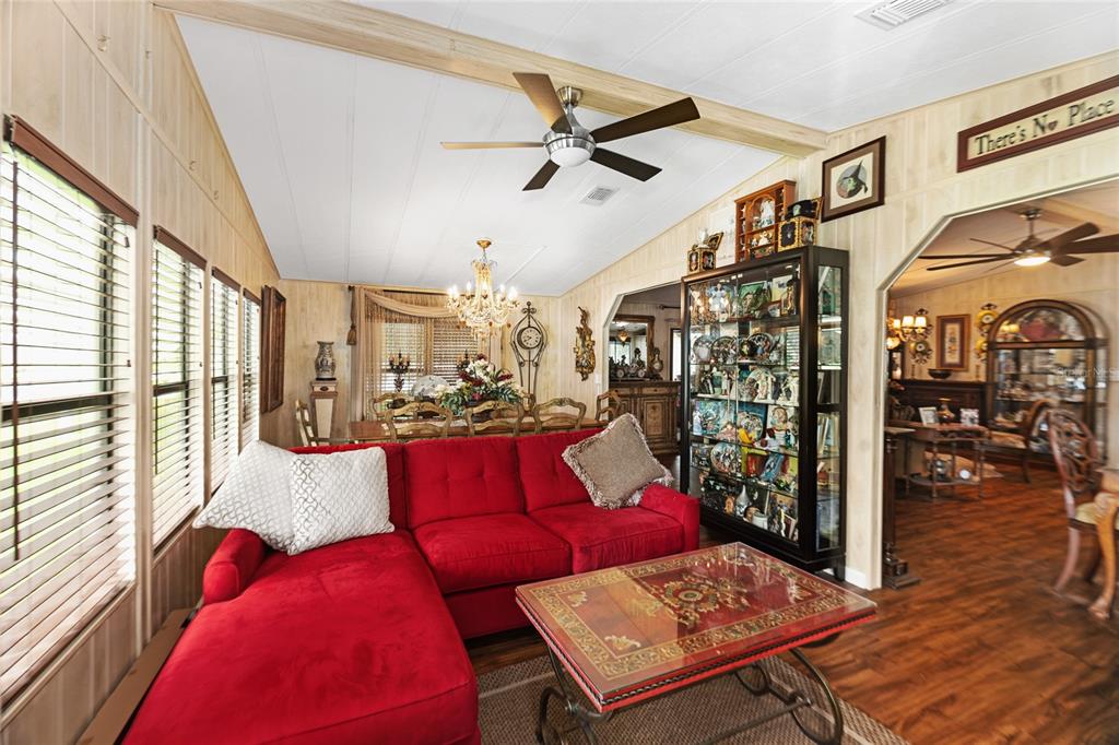 A living room features a red sectional sofa, a glass-topped coffee table, and wood-paneled walls — 2002 S CITRUS CIRCLE UNIT 1728, ZELLWOOD, FL