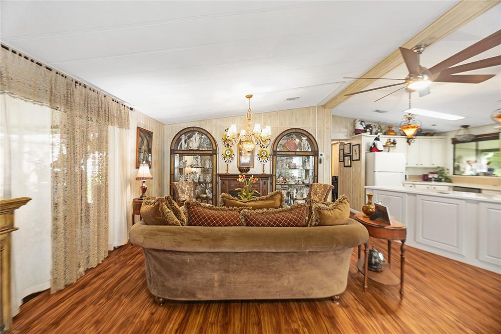 A living room with wood-look flooring, a brown sofa, and two arched display cabinets — 2002 S CITRUS CIRCLE UNIT 1728, ZELLWOOD, FL