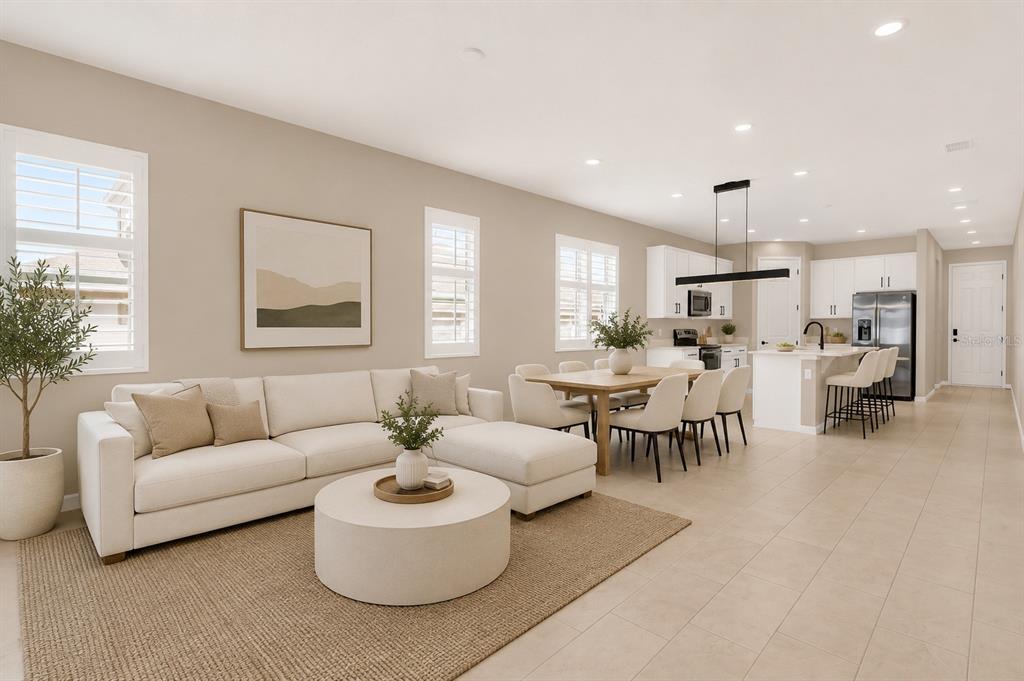 An open-concept living room and kitchen featuring a white sectional, dining table, and kitchen island — 3998 BANNOCK AVENUE, TAVARES, FL
