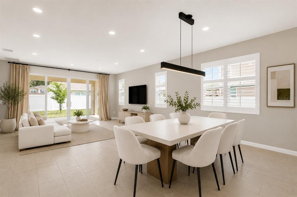 A bright, open-concept living and dining area features light tile floors and modern neutral decor — 3998 BANNOCK AVENUE, TAVARES, FL