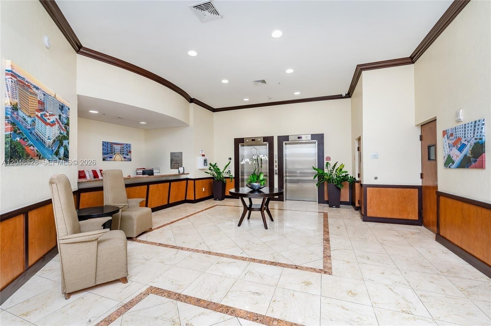 A lobby features a reception desk, two elevators, tiled floors, and beige armchairs — 2030 S Douglas Rd # 716, Coral Gables FL 33134, CORAL GABLES, FL
