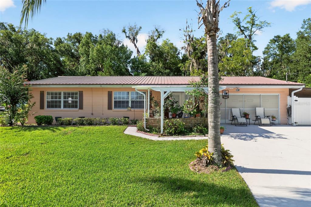 A single-story house with a metal roof, peach-colored siding, and a front patio area — 2840 SE 2ND STREET, OCALA, FL