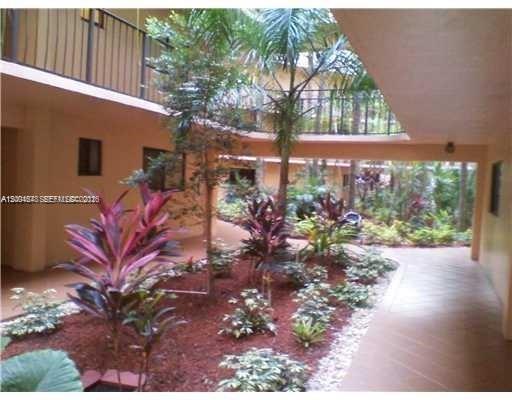 A landscaped courtyard with tropical plants and palm trees sits between two levels of apartment balconies — 8600 SW 133rd Ave Rd # 413, Miami FL 33183, MIAMI, FL