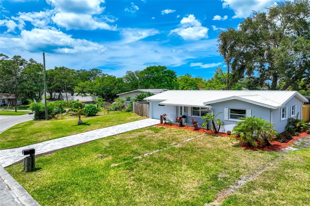 A single-story house with a white metal roof and a paved walkway in the yard — 3579 POCAHONTAS DRIVE, LARGO, FL