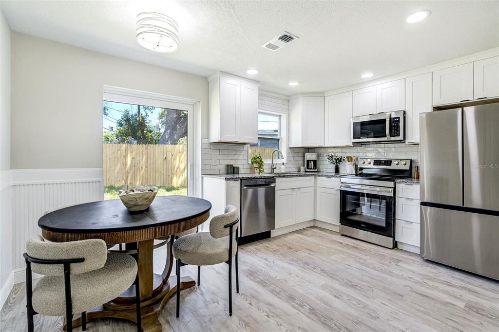 A kitchen with white cabinets, stainless steel appliances, and a round dining table — 3579 POCAHONTAS DRIVE, LARGO, FL