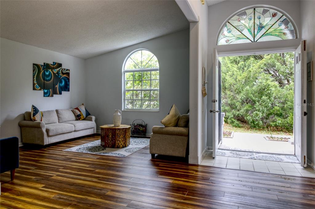 A living room features wood-look flooring, a sofa, an armchair, and an open front door — 2 SEAGIRT COURT, PALM COAST, FL
