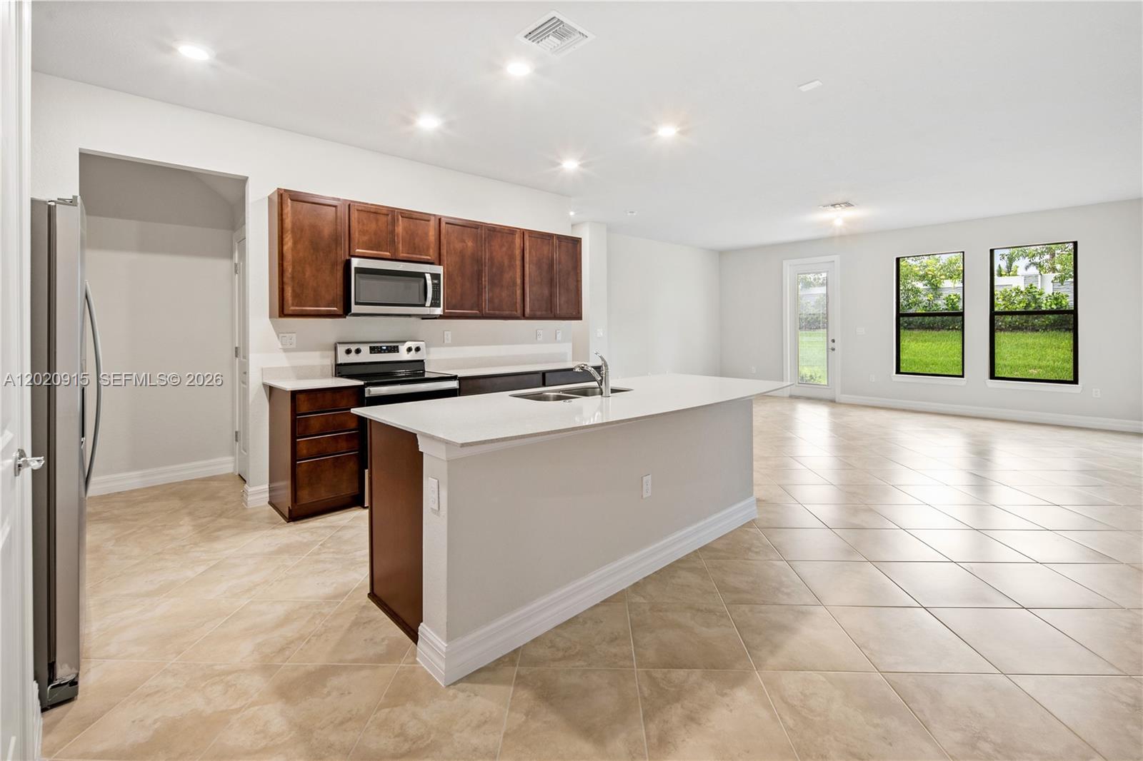 A kitchen features dark wood cabinets, white countertops, a central island, and tile flooring — 4488 E Appleton Cir E, Oakland Park FL 33309, OAKLAND PARK, FL
